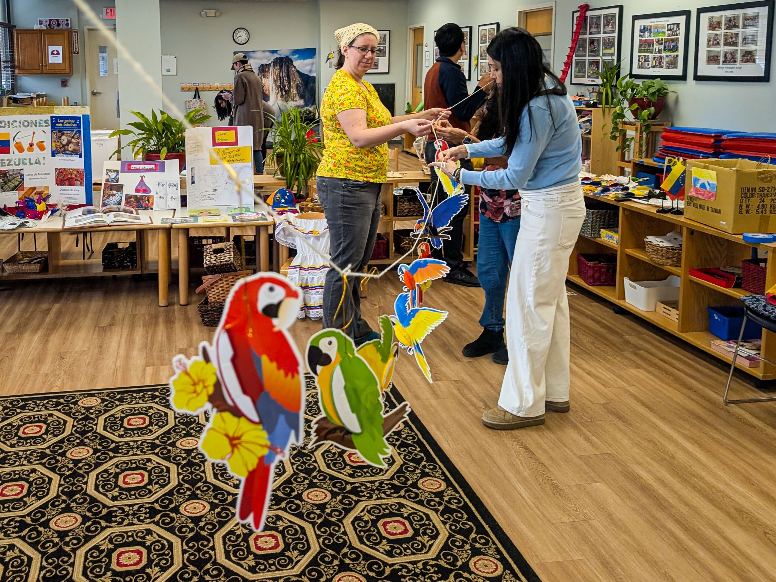 PXL_20260413_124119386 Parent volunteers stringing decorations for the Venezuela celebration